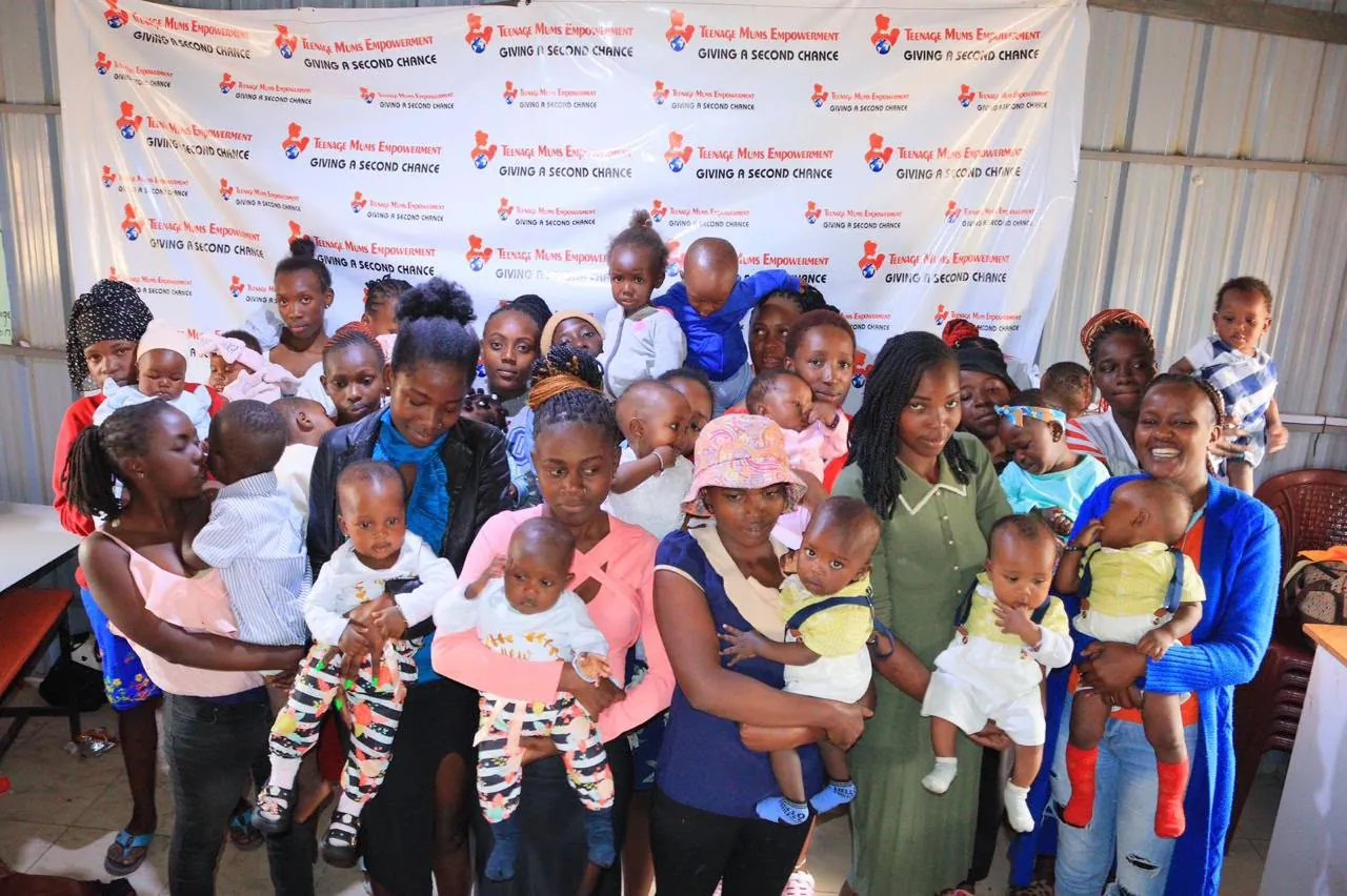 Young mothers holding their babies in front of the Teenage Mums Empowerment backdrop