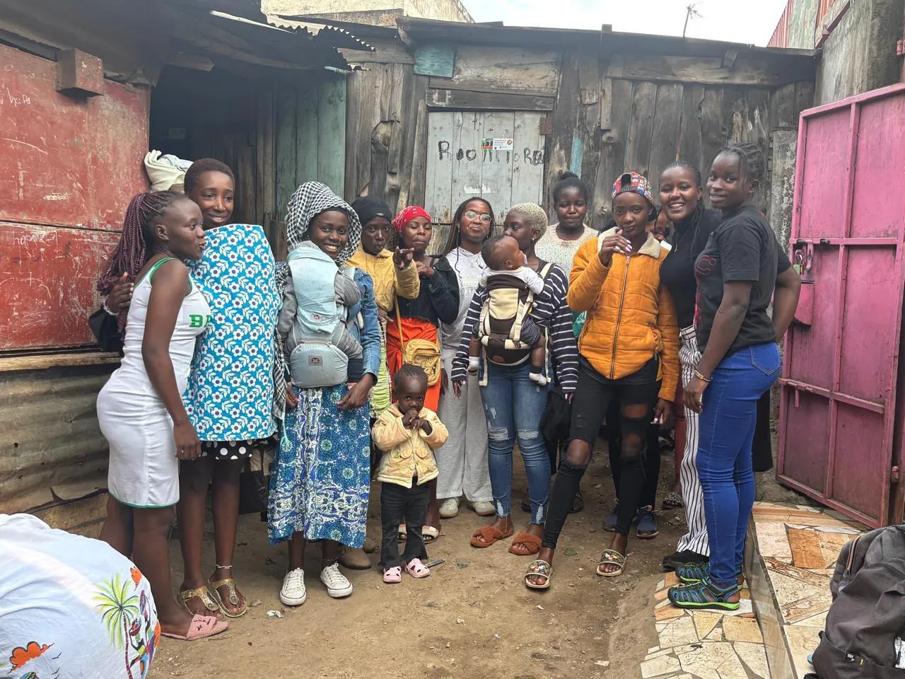 Members standing together outside, some carrying babies on their backs