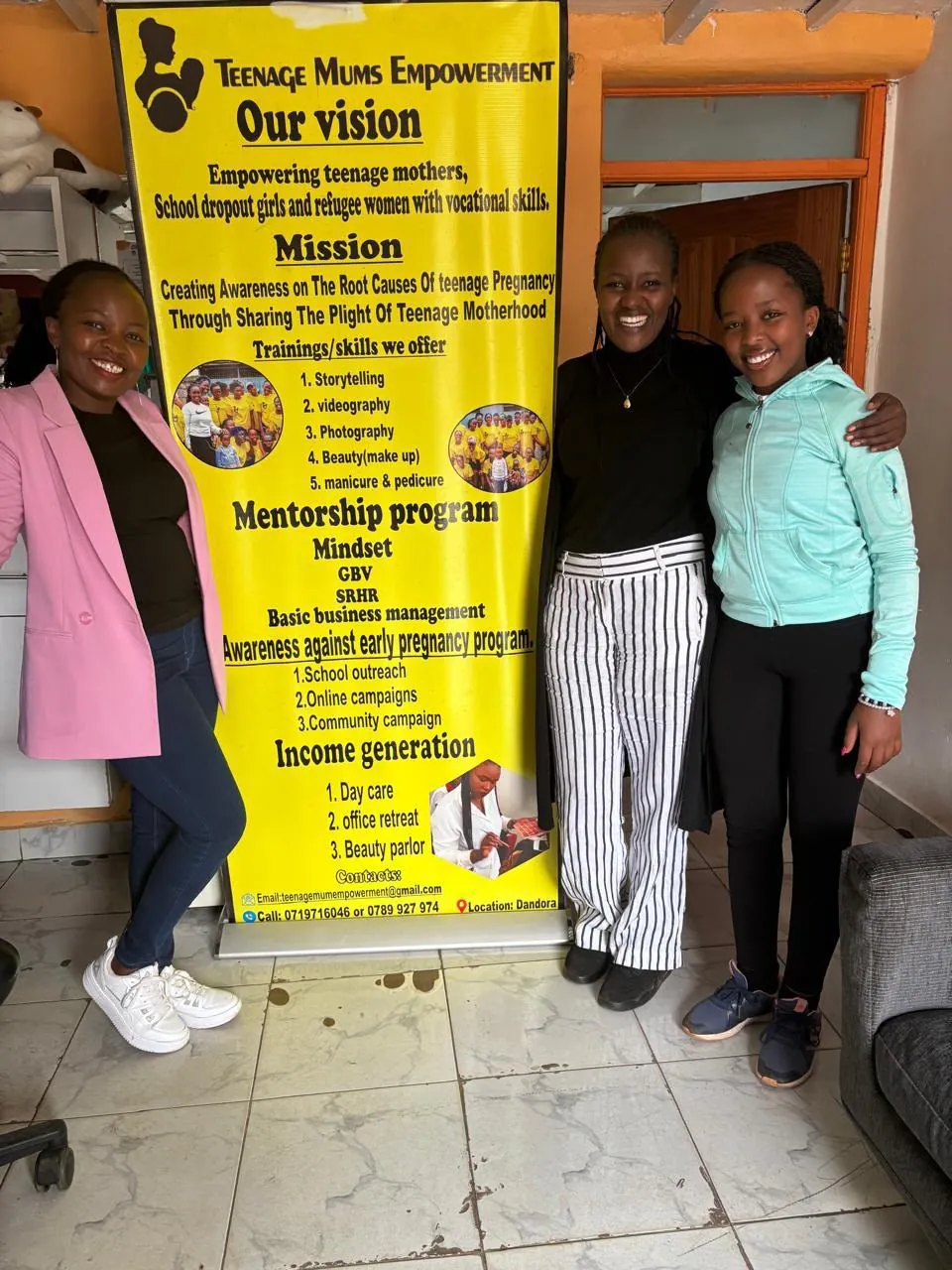 A smiling team member beside the banner listing the organisation’s vision, mission and programmes